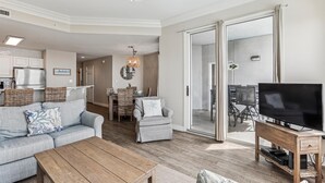 Un salon moderne comprenant un canapé, une table basse, un téléviseur et un coin repas avec des chaises et une table.