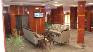 A lobby with a sofa, armchairs, a coffee table, and a television mounted on the wall. - K-class Hotel (Abuja)