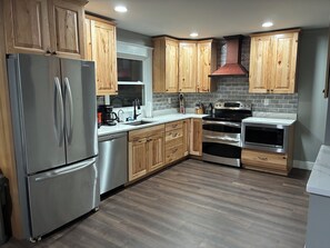 A modern kitchen with wooden cabinets, stainless steel appliances, and a tiled backsplash.