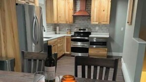 Una cocina con armarios de madera, un refrigerador de acero inoxidable y una mesa de comedor con un posavasos de madera.