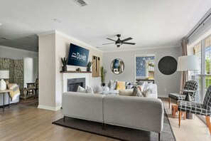 Una sala de estar moderna con un sofá gris, una chimenea y un ventanal con cortinas.