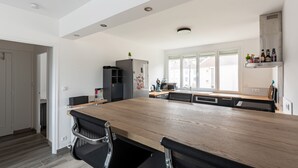 Una cocina moderna con una gran mesa de madera, sillas negras y un horno empotrado.
