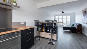 Una cocina moderna con horno integrado, encimera de madera y una zona de bar con taburetes.