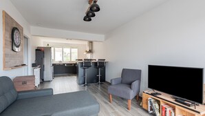 Una sala de estar moderna con un sofá gris, un sillón gris, un televisor de pantalla plana y una estantería.