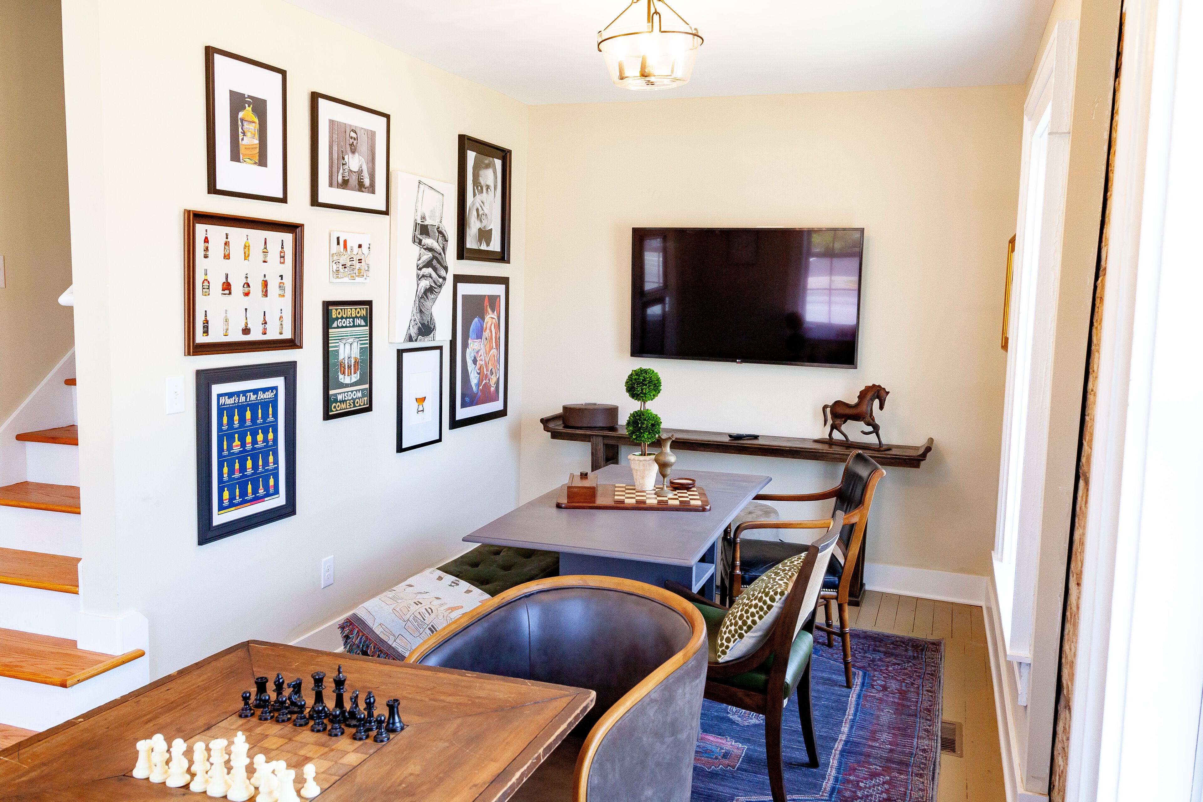 Un salon avec un jeu d’échecs, un téléviseur et divers tableaux encadrés accrochés au mur.