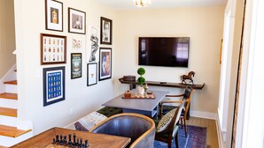 Una sala de estar con un tablero de ajedrez, un televisor y varias fotografías enmarcadas en la pared.