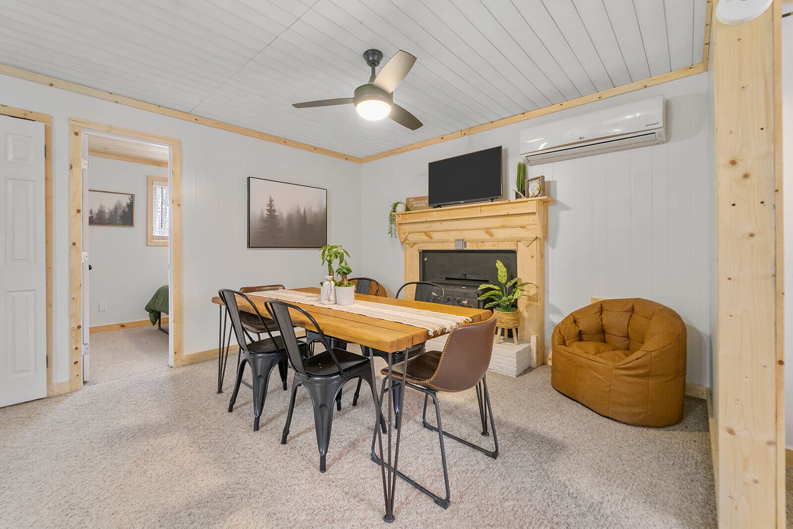 A cozy room with a wooden dining table, chairs, a fireplace, a television, and a bean bag chair.