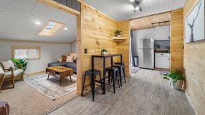 A cozy cabin interior with a dining area, kitchen, and a loft bedroom with a skylight. - 🔥hot tub, view, 🐕 friendly modern cabin (New Market)