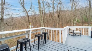 A deck with a white railing, black barstools, and a bench. - 🔥hot tub, view, 🐕 friendly modern cabin (New Market)