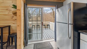 A compact kitchen with a built-in stainless steel refrigerator, a wooden deck, and a sliding glass door leading to an outdoor seating area. - 🔥hot tub, view, 🐕 friendly modern cabin (New Market)