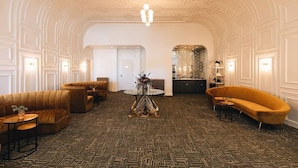 A spacious lobby with a patterned carpet, a central round table, and two sofas.