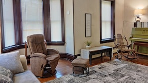 A living room with a brown leather chair, a small table, a bench, and a green piano. - The Ole Farmhouse at Warm Springs  - Country Living For the Whole Family (Landisburg)