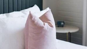 A neatly made bed with white linens and a single pink pillow. - Glenmary Suite 204 at The Bellwether Hotel (Louisville)