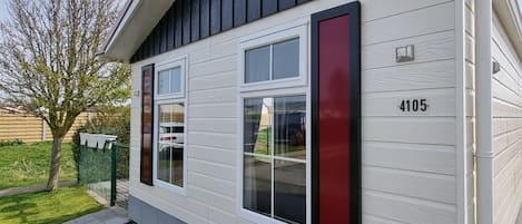 A house with a number 4105 on the side, a garage door, and a small garden area with a tree and mulch.