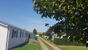 Reihle von weißen Mobilheimen mit grünen Rasenflächen und einem gepflasterten Weg dazwischen.