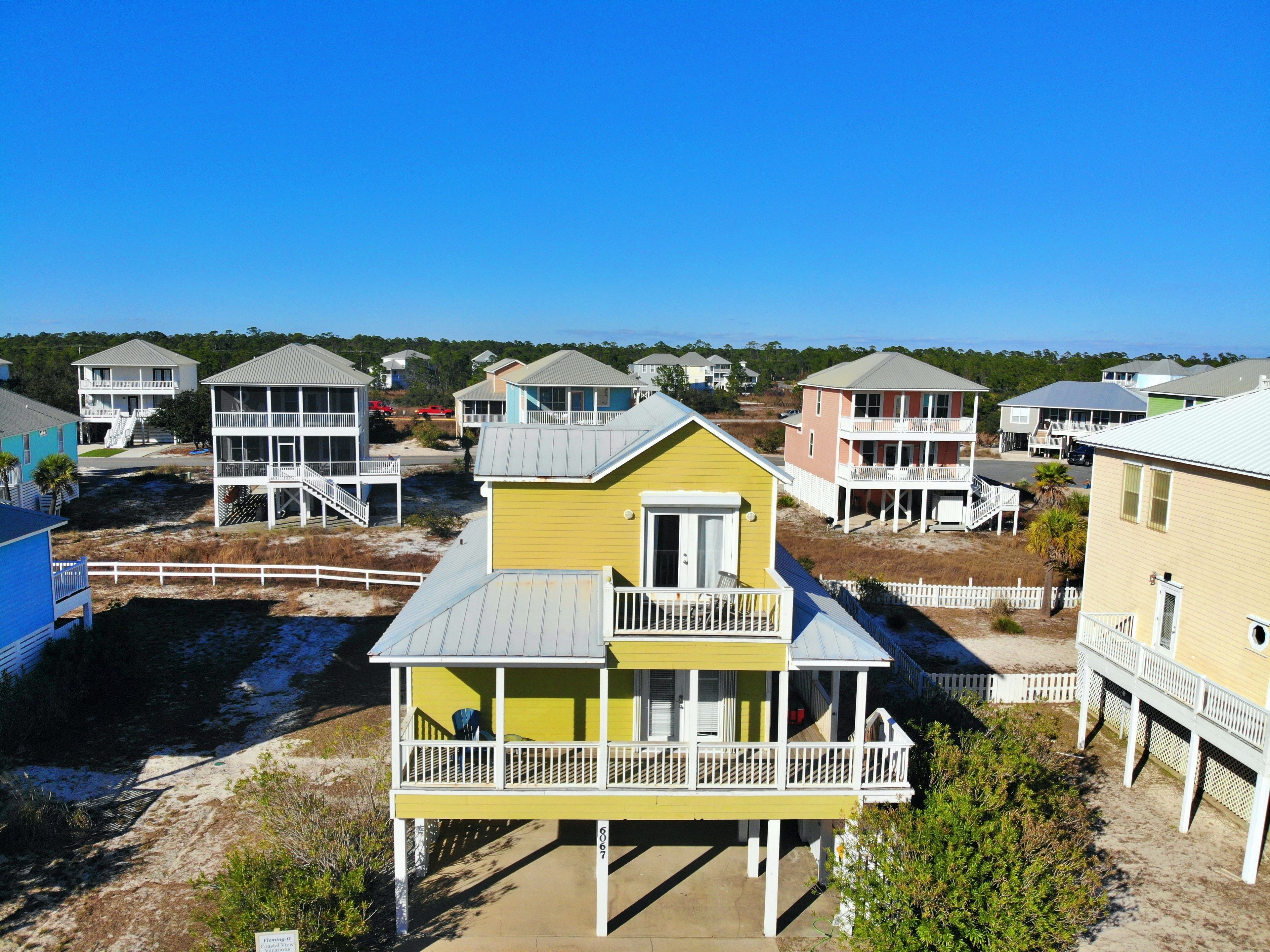 A coastal residential area with multiple two-story houses featuring balconies and a sandy beach in the foreground.