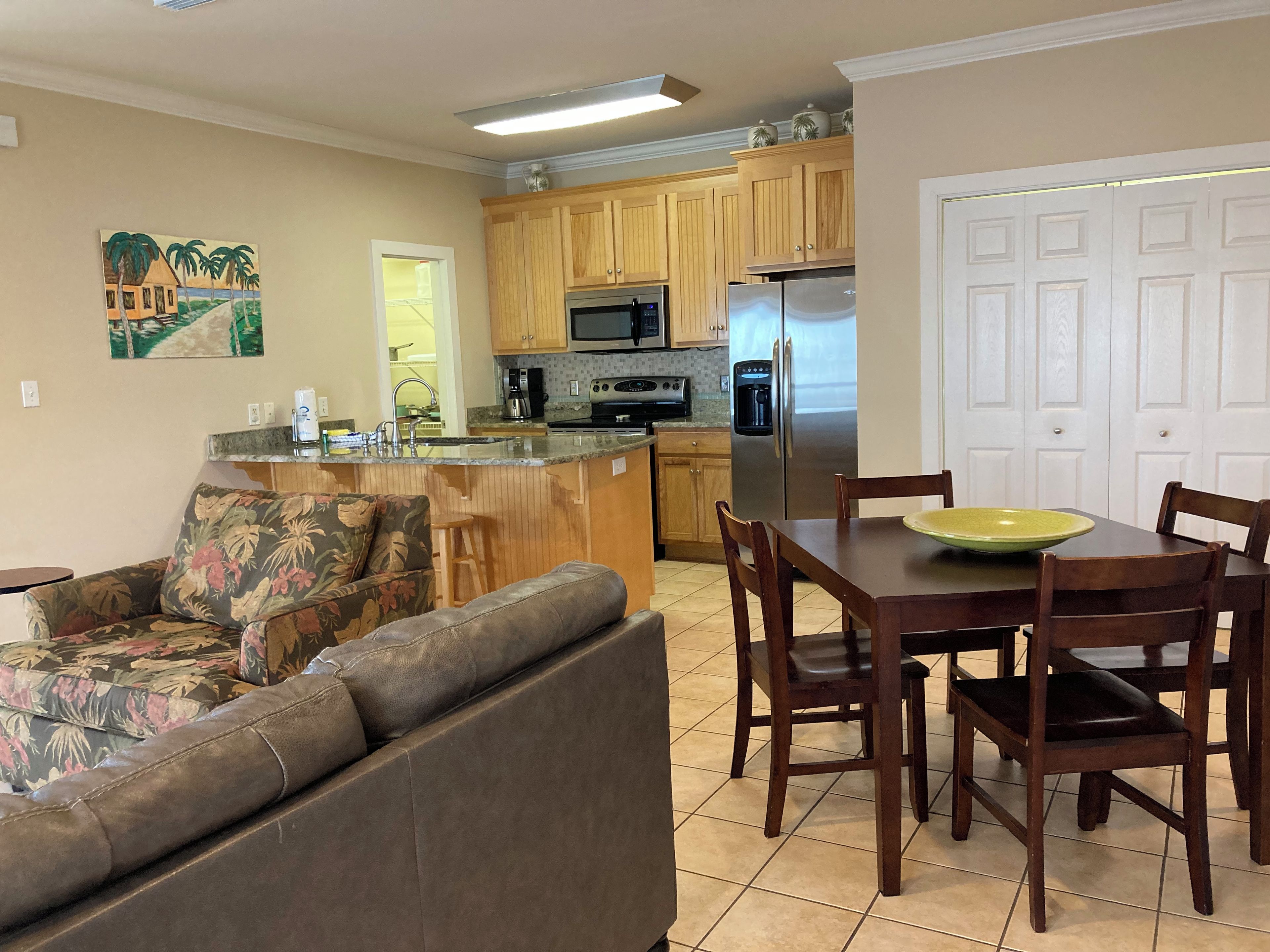 A compact living space with a kitchenette, a dining area with a table and chairs, a sofa, and a door.