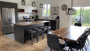 A modern kitchen with a central island, bar stools, and a dining table with chairs.