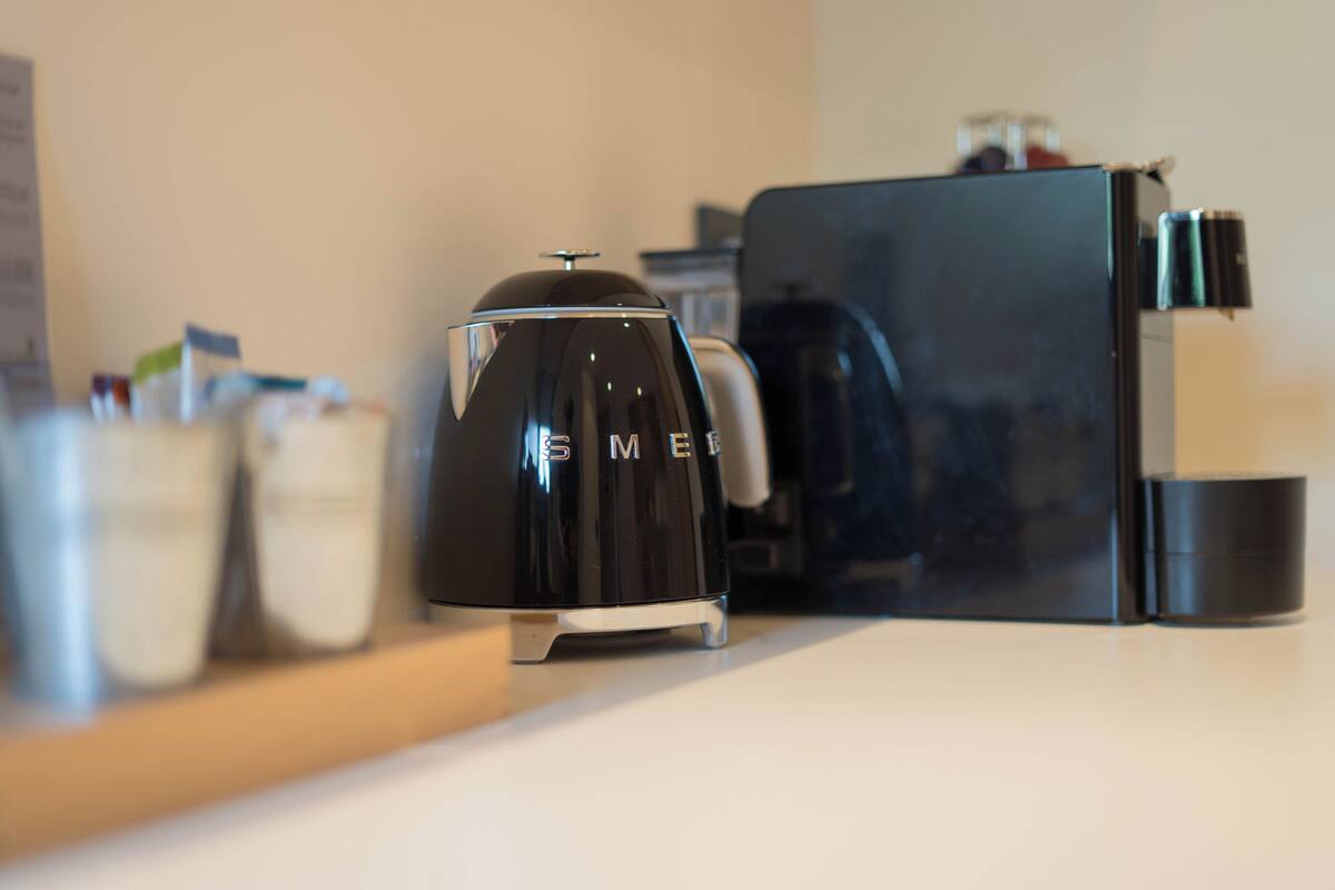 A modern kitchen with a black coffee maker, a black refrigerator, and a white countertop.