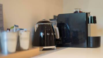 A modern kitchen with a black coffee maker, a black refrigerator, and a white countertop.