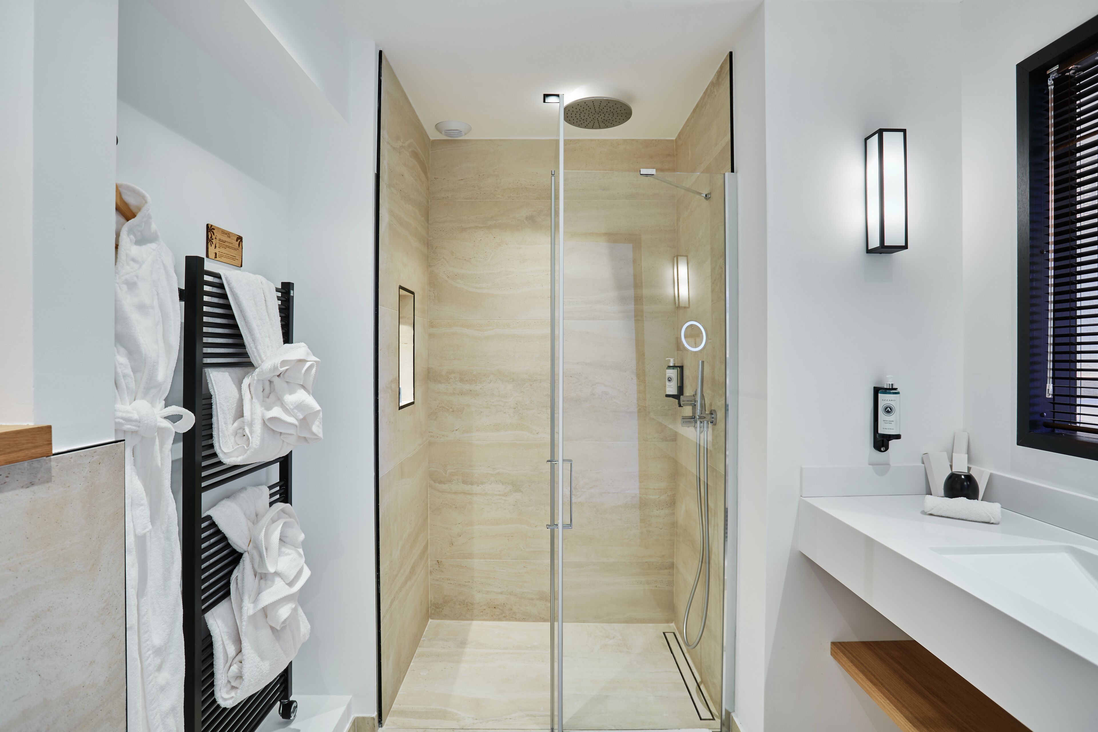 Ein modernes Badezimmer mit einer Glaskabine zur Dusche, einem weißen Waschbecken und einem Handtuchhalter mit ordentlich gefalteten Handtüchern.