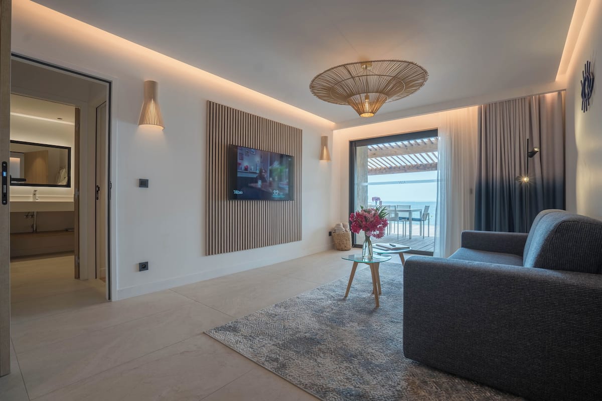 A modern living room with a flat-screen TV, a sofa, a glass coffee table, and a decorative vase.