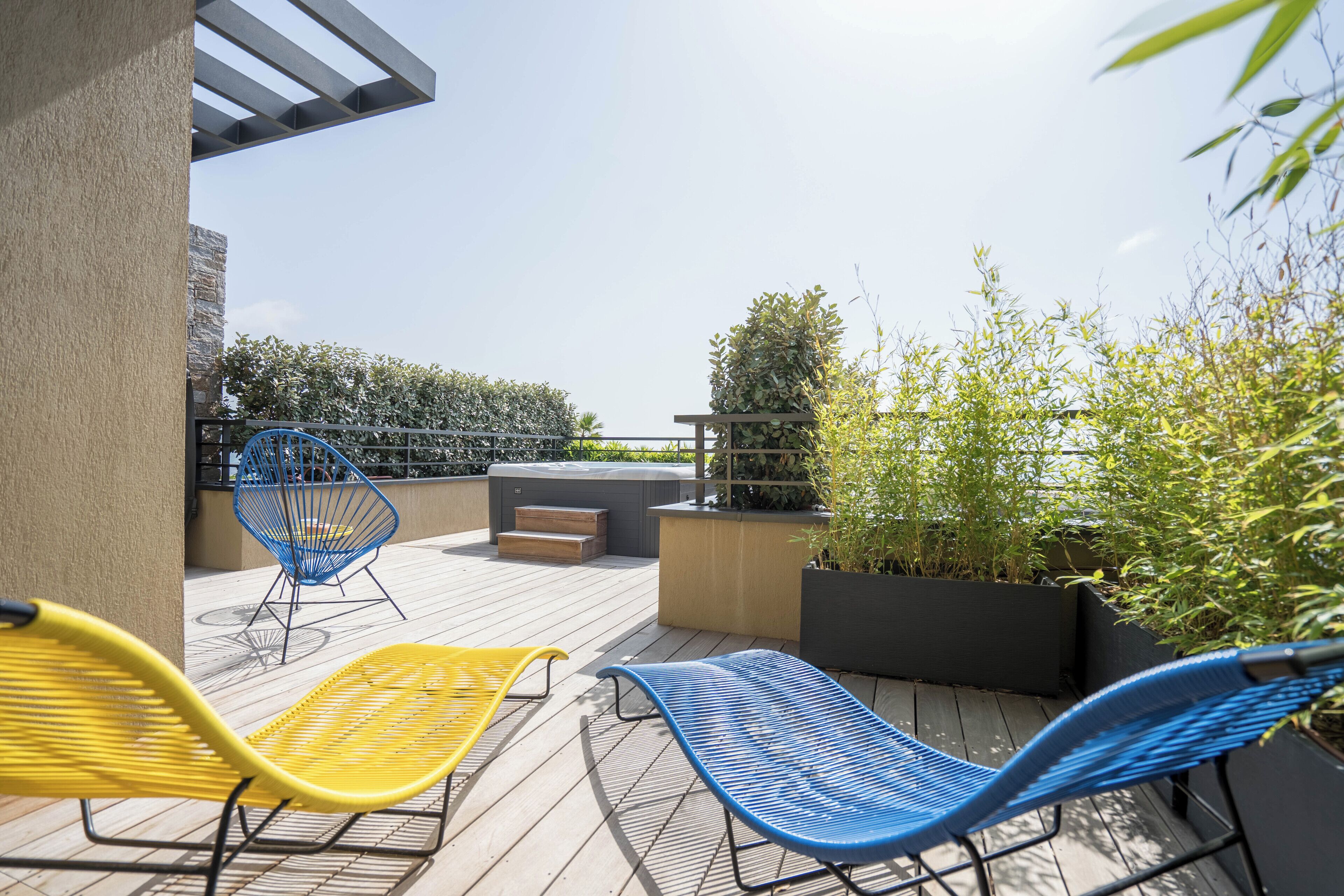 Una terraza en la azotea con asientos al aire libre, una pérgola y plantas en macetas.