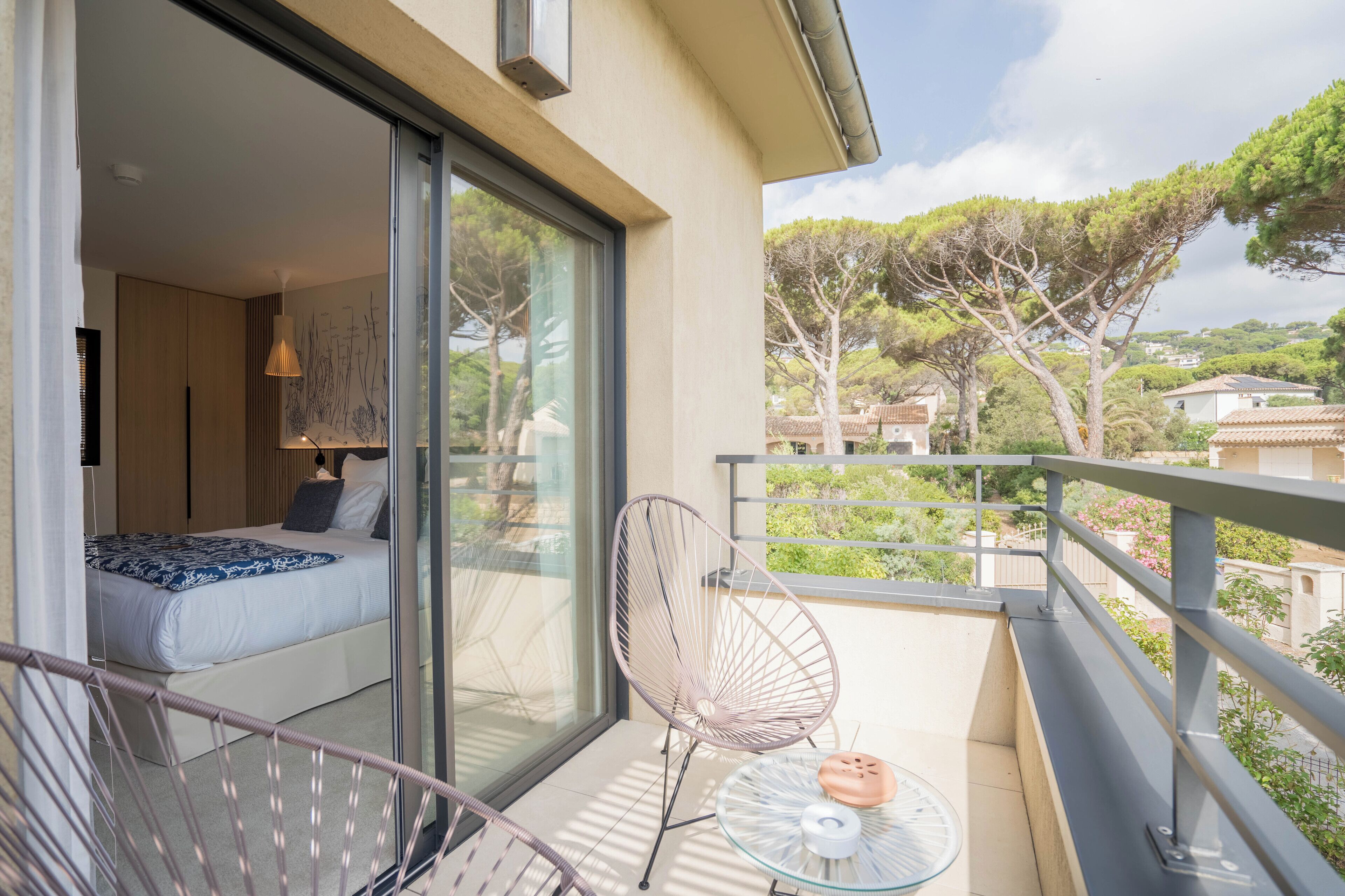 A balcony with a bed, a chair, and a small table.
