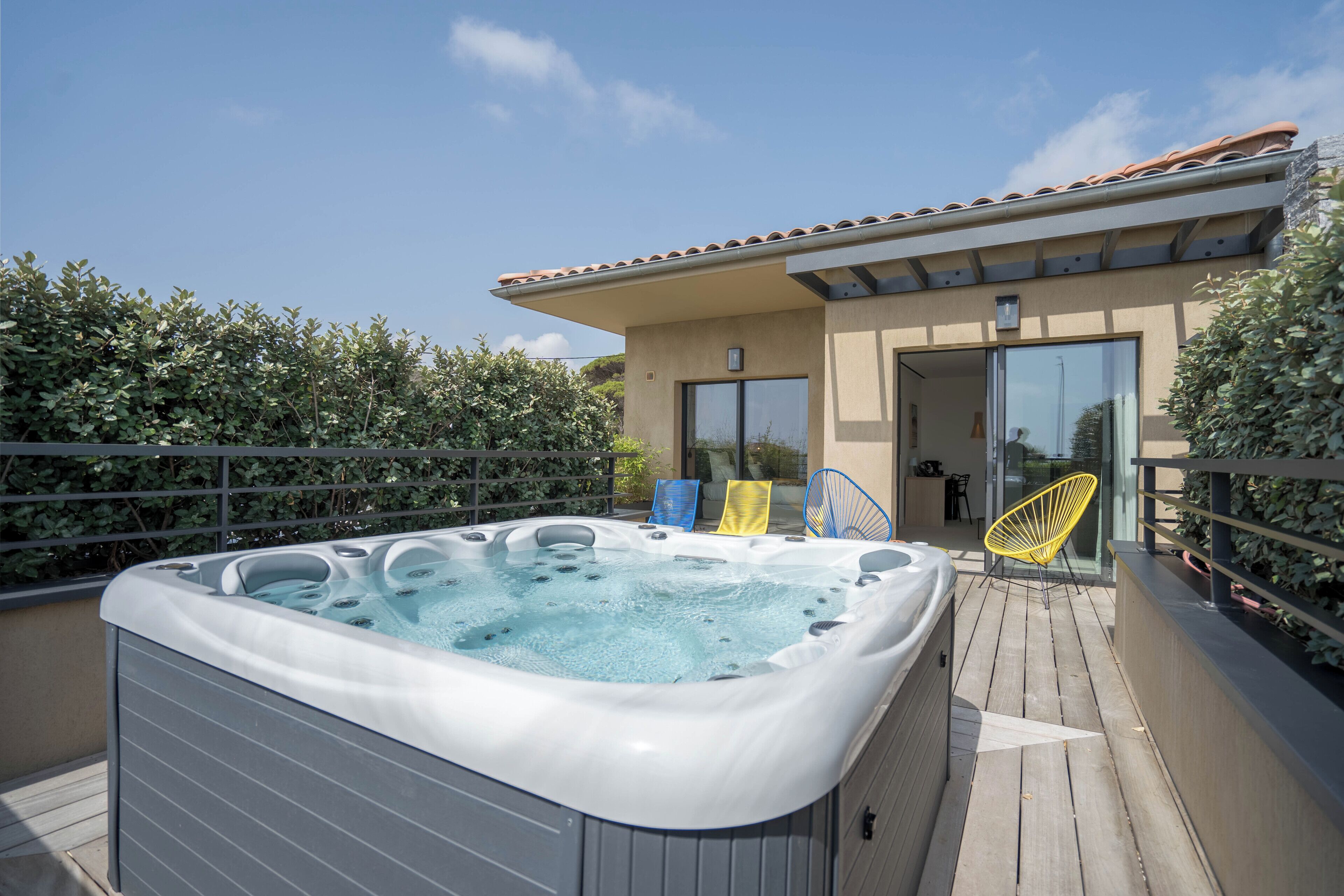 A hot tub on a wooden deck with a building in the background.