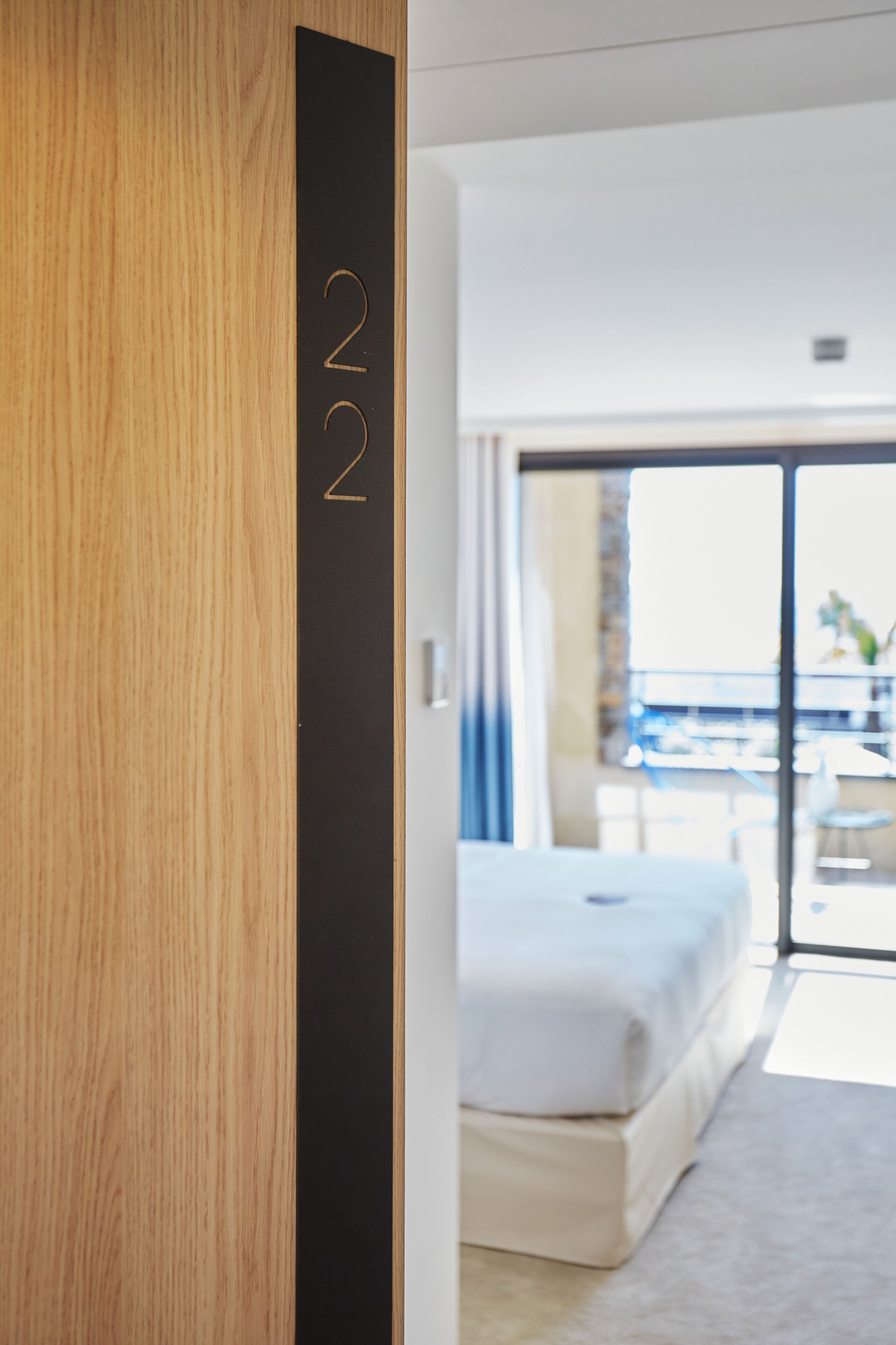 Une chambre d’hôtel moderne avec un grand lit, une porte en bois et un balcon offrant une vue agréable.