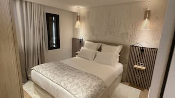 Un dormitorio moderno con una cama grande, dos mesitas de noche con lámparas, una ventana y un mural en la pared.