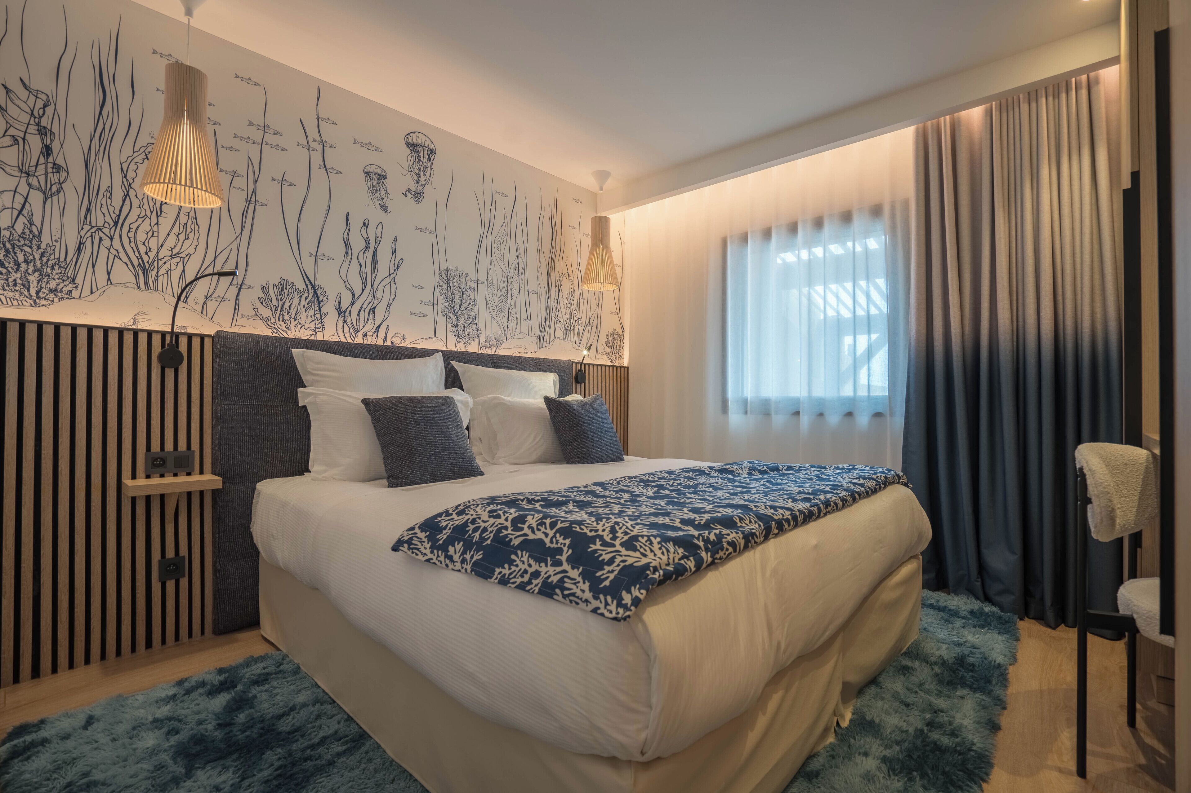 A modern bedroom with a large bed, a wall mural, and a window with curtains.