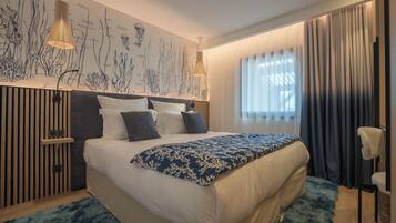 A modern bedroom with a large bed, a wall mural, and a window with curtains.