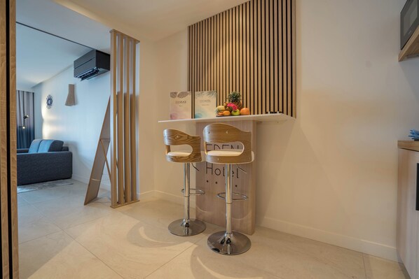 A modern hotel lobby with two bar stools, a wooden reception desk, and a fruit display. -  Eden Hotel (Sainte-Maxime)