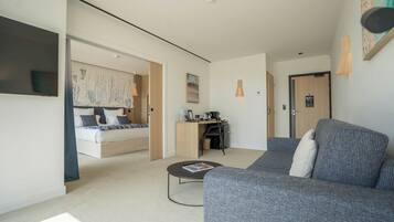 Una habitación de hotel moderna con una cama, un sofá, un escritorio y una pequeña mesa de centro.