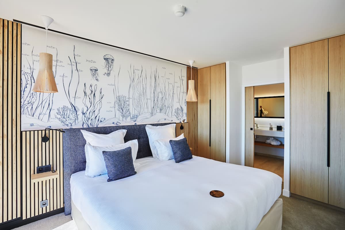 A modern bedroom with a large bed, a wall mural, and built-in wooden cabinets.