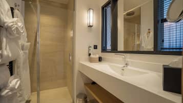 A modern bathroom with a glass-enclosed shower, a large mirror, and a white sink.