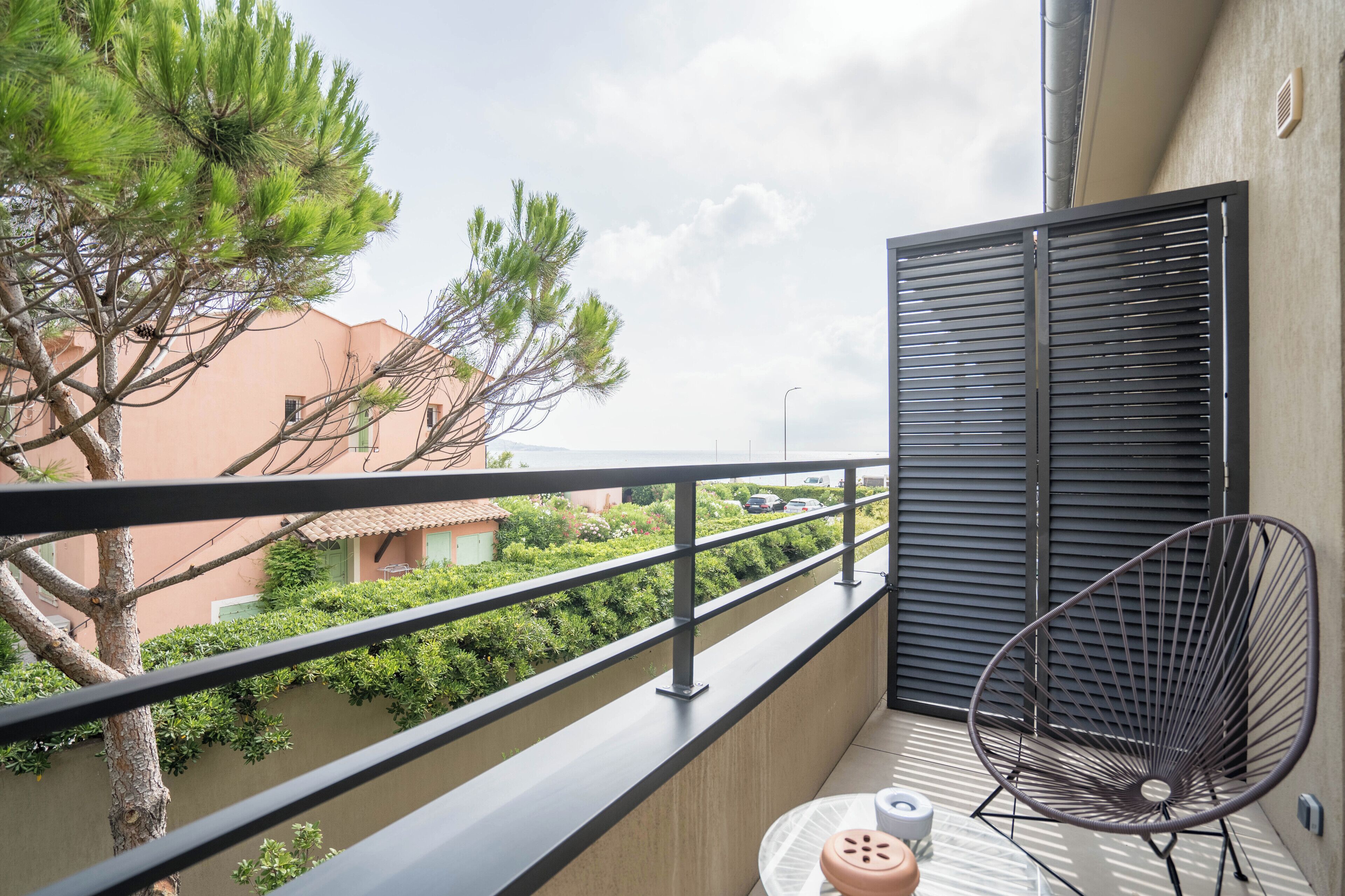 A balcony with a metal chair, a small table, and a potted plant.