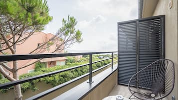 A balcony with a metal chair, a small table, and a potted plant.