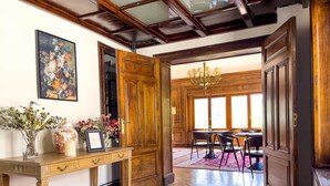A wooden interior with a desk, a chandelier, and a dining area with chairs and a table. - Angelats Hotel (Ribes De Freser)