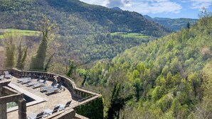 A terrace with lounge chairs overlooking a valley with dense forest and hills. - Angelats Hotel (Ribes De Freser)