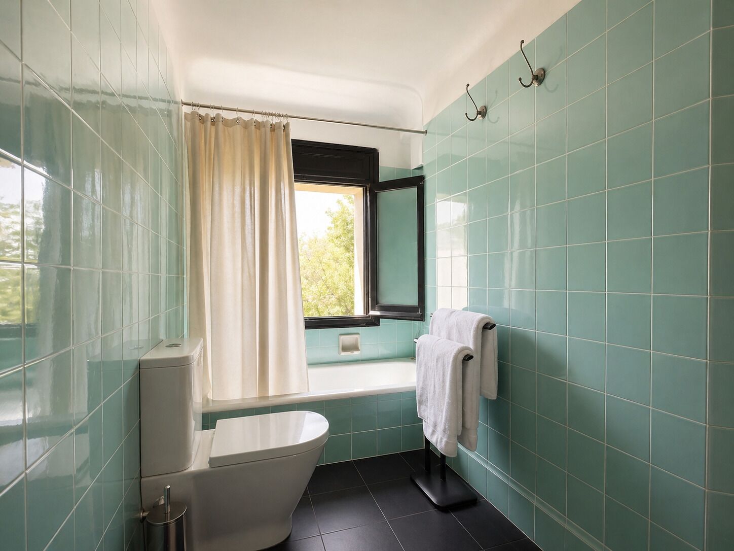 A bathroom with a bathtub, toilet, and a window with curtains.