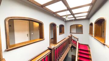 Un magnifique escalier, avec un tapis rouge, des rampes en bois et une verrière au-dessus.