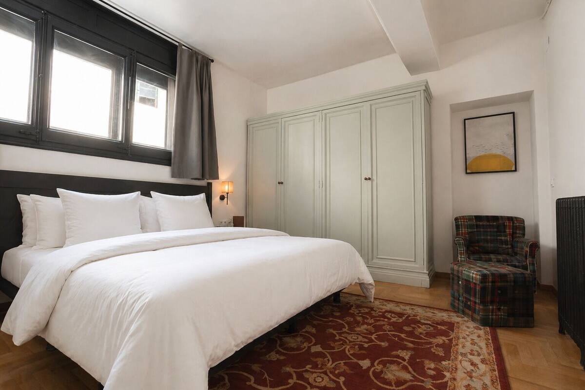 Een slaapkamer met een groot bed, een kledingkast, een stoel en een radiator.