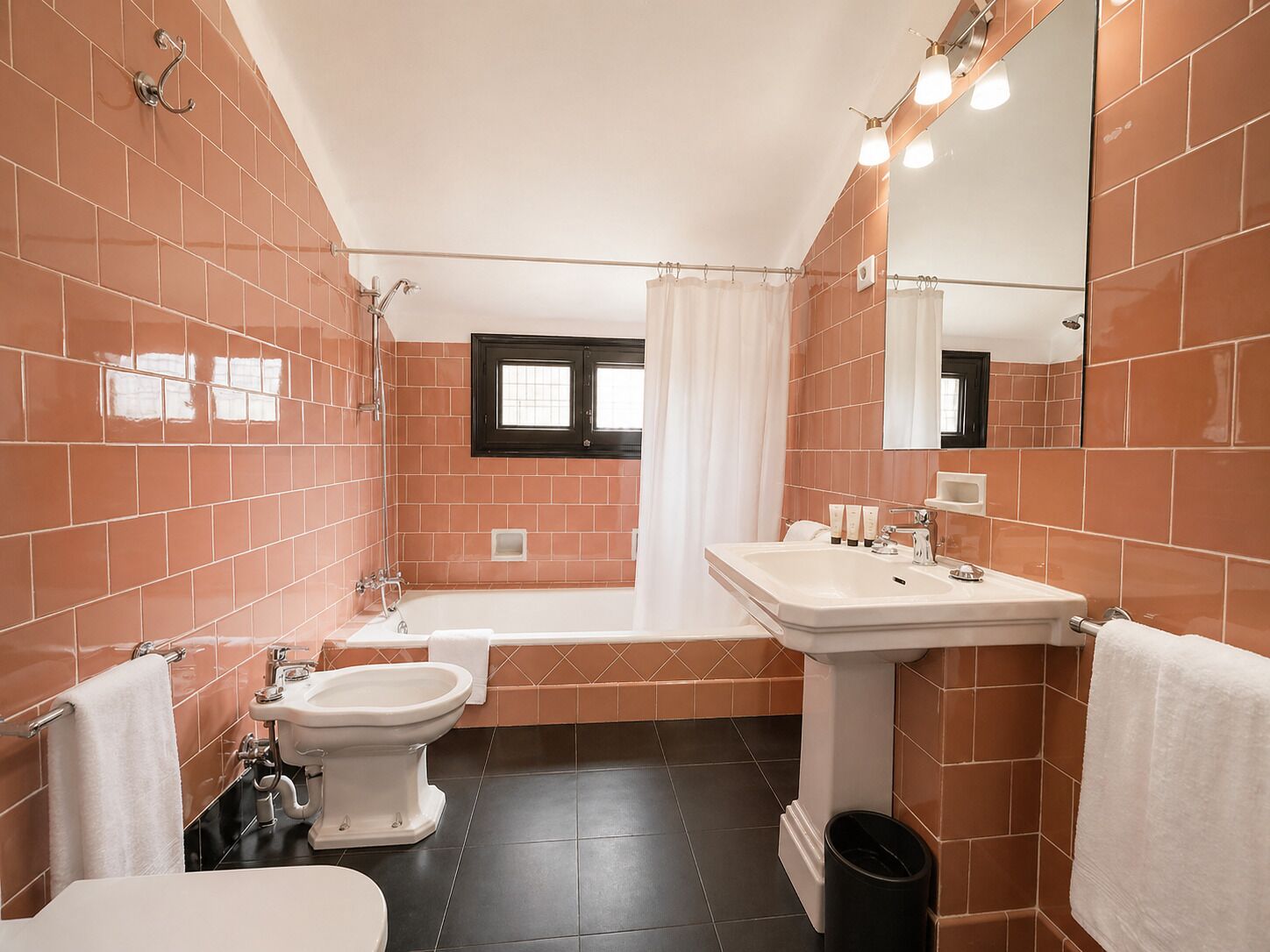 Une salle de bain comprenant une baignoire, des toilettes, un bidet, un lavabo et un miroir.