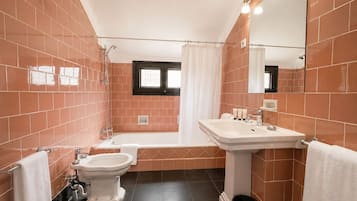 Une salle de bain comprenant une baignoire, des toilettes, un bidet, un lavabo et un miroir.
