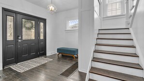 Een modern interieur met een donkere houten trap, een blauwe bank en een geometrisch armatuur.