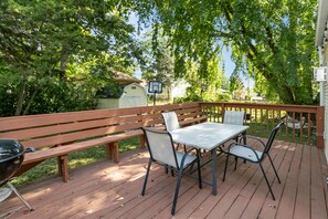 An outdoor deck with a table and chairs, a barbecue grill, and a basketball hoop.