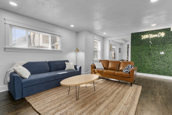 A modern living room with a blue sofa, a brown leather sofa, and a round coffee table.