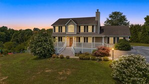 A two-story house with a front porch, a chimney, and a well-maintained lawn. - Castlewood Retreat | Views, Hot Tub & Foosball Table🛁🏔️ + Biltmore Pass (Alexander)